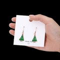 Festliche grün-goldene Weihnachtsbaum-Ohrhänger auf weißer Karte in der Hand - Weihnachtsbaum Stil 01