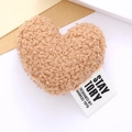 Close-up of khaki plush heart accessory with teddy fleece texture and white fabric label - Khaki
