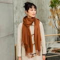 Caramel cashmere-like long scarf with fringes paired with beige coat in outdoor setting - Camel