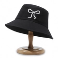 Black cotton bucket hat with white 3D bow decoration on a spherical wooden stand - Black