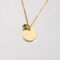 Close-up of golden mirror-finish round pendant with an inlaid green gemstone charm - 8# Birthstone