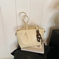 Bolso tote beige plisado con amuleto de chocolate sobre un fondo blanco minimalista - Sin colgante / Blanco