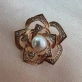 Macro shot of gold hollowed-out camellia brooch with crystal petals and pearl center - Plum Tassel Brooch