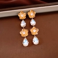 Détail de boucles d'oreilles fleurs plaquées or 18K avec pampilles en cristal sur fond vintage - Transparent