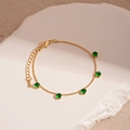 Dettaglio del bracciale a sfere dorate con cinque zirconi verdi su vassoio in pietra bianca - Stile Catena Sottile con Zircone Verde (8#)