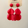 Detail of red tiered petal earrings with fine textures on a brown display card - Red