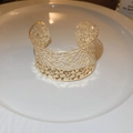 Detailed view of wide open gold cuff bracelet with irregular hollow texture on white plate - Gold Hollow Irregular Texture Style