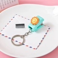 Mini mint green stapler keychain with sunflower design and staples on pink background - Smiling Sun