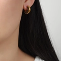 Elegant gold hoop earrings with green pave-set zircons on female model's ear - Gold Green Zirconia