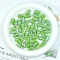 Macro shot of green fish-shaped ceramic beads for DIY jewelry making in a white tray - Green