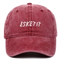 Close-up of white ESKETIT letter embroidery on a washed red cotton baseball cap - Burgundy