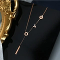Macro shot of rose gold LOVE letter necklace with a vertical bar pendant on black surface - Rose Gold