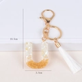 Detail view of initial U keychain with shell flakes, gold foil and white silk tassel - Letter U