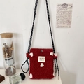 Detail of red fleece phone bag with white hearts and woven strap on white wall background - Red Heart Jacquard