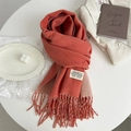 Detail of coral orange cashmere-like scarf with fringe edges and brand label on fabric - Bright Orange