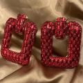 Macro detail of red rhinestone pavé on gold chain earrings over champagne silk fabric - Red Square