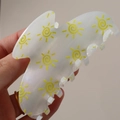 White acrylic hair claw clip with yellow sun pattern held against a beige background - Yellow Sun (H591)