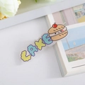 Detail of cute acrylic cake hair clip featuring macaron colors and cartoon illustration - Cake Design