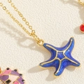 Macro shot of blue enamel starfish pendant with gold chain on textured background - Blue Starfish