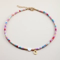 Detail of colorful beaded necklace with white heart shell and gold letter O pendant - Letter O