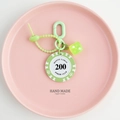 Detail of green poker chip and translucent dice keychain on a pink display tray - Green-200 Value