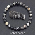 Macro shot of polished Zebra Stone beaded bracelet with a raw textured mineral sample - Zebra Stone