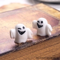 Close-up of two mini 3D ceramic ghost figurines on a vintage book for Halloween decor - Big Mouth Smile White Ghost