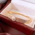 Detaillierte Makroansicht des 18K vergoldeten geflochtenen Armbands mit Zirkonia-Blüte - Gold
