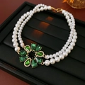 Primo piano di collana di perle a doppio strato con gemma verde e pendente dorato - Collana / Oro Verde
