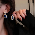Close-up of gold-plated earrings with rectangle deep blue gemstone on a model - Earrings / Emerald Green Gold