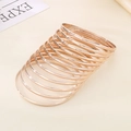 Close-up of 12-piece set rose gold 3.6mm polished stainless steel bangles stacked on a table - Inner Diameter 68mm / Set of 12 / Rose Gold