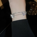 Détail d'un bracelet papillon double couche en zircon sur le poignet avec un éclat métallique - Papillon Double Couche Géométrique