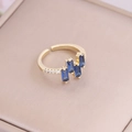 Dettaglio macro dell'anello in oro 18K con tre pietre di zircone blu rettangolari - Aperto Regolabile / Blu Reale