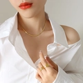 Goldene Schlangenkette aus Titanstahl und strukturierte Ringe an Model in weißer Bluse - Halskette / 37+8cm / Gold
