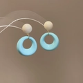 Makroaufnahme von himmelblauen Harz-Ohrringen mit cremefarbenem Stecker und Goldring - 925 Silber Nadel Himmelblauer Hohlring Weiße Perle