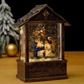 Close-up of bronze Christmas lantern featuring a Nativity scene with swirling glitter - Angel