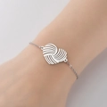 Close-up of a silver stainless steel chain bracelet with a woven heart pendant on a wrist - Steel
