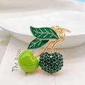 Dettaglio macro del portachiavi a ciliegia con strass verdi e finitura dorata - Verde