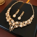 Dettaglio di collana dorata di lusso e orecchini a goccia con strass scintillanti - Oro