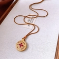 Dettaglio di un ciondolo floreale vintage in oro con zirconi e rubini su cordino - Marrone oro