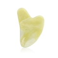Macro shot of heart-shaped jade gua sha board with smooth texture and pale yellow finish - Jade / Lemon Yellow