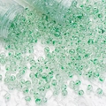 Close-up of clear glass beads with green floral patterns spilling from a tube - 8mm Spotted Beads / Green