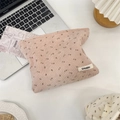 Detailopname van roze corduroy make-uptas met bloemenprint en een geweven merklabel - Roze