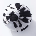 Close-up of baby top knot hat featuring a classic black and white cow print pattern - Style B (Black and White Cow)