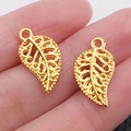 Golden hollowed leaf-shaped alloy charms for DIY jewelry making on human palm - Gold