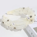 Detail of cream tulle headband with sparkling rhinestones and white pearls on a book - Pearl Rhinestone Knotted Cream
