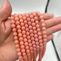 Peach pink luminous stone round beads for DIY jewelry making shown in hand bundle - Pink Luminous Stone