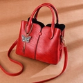 Sac à main rétro rouge avec breloque nœud et texture grainée en vue latérale diagonale - Rouge
