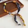 Dettaglio della collana bohémien con strisce di tessuto floreale e perle artigianali - Stile Perlina Colorata