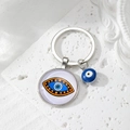 Close-up of silver Evil Eye keychain with glass pendant and blue bead on stone surface - 8# Brown Dot Eye